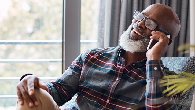 A man sits back and smiles while he talks on a smartphone. See how to contact the disability advocates at Mathis & Mathis.