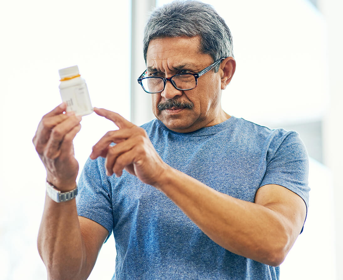 A man studies the label on a pill bottle.