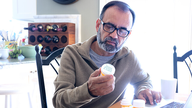 A man sits at a kitchen table, studying pill bottles. This page discusses the chances of receiving Social Security Disability benefits.