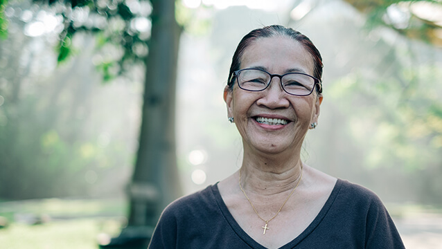 A woman stands in a park, smiling. There are small differences in how Social Security Disability works in Maryland, Virginia and D.C.