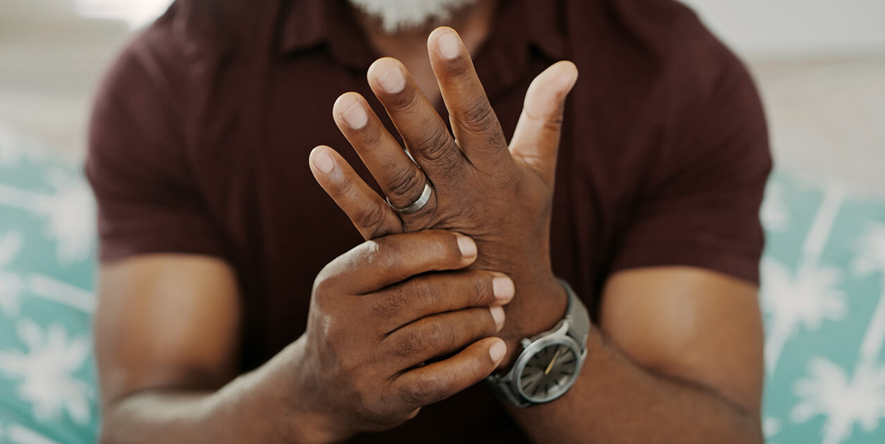 A man rubs his left hand with his right hand. You could get disability benefits for arthritis.