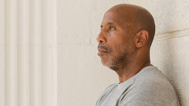 A man stands against a stone wall, arms crossed, looking into the distance. When you're denied disability benefits, you can pursue a Social Security Disability appeal.