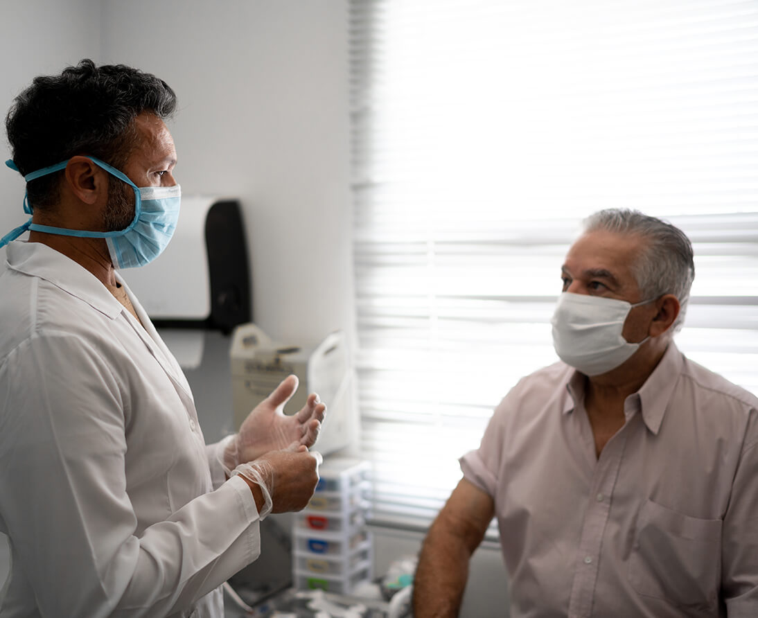 A man sits on an examining table, talking to a doctor.