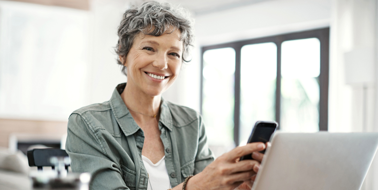 A woman smiling and holding her phone.